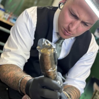 An artist at Until Ink Do Us Part tattooing a client in the studio